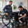 Custom ultralight rigid wheelchair being professionally adjusted for a client in a home setting